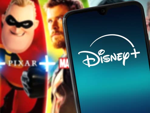 Disney+ auf einem Handy dahinter einige Shows des Anbieters