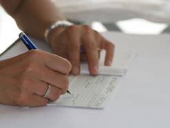 Eine Frau unterschreibt ein Dokument (Symbolbild)
