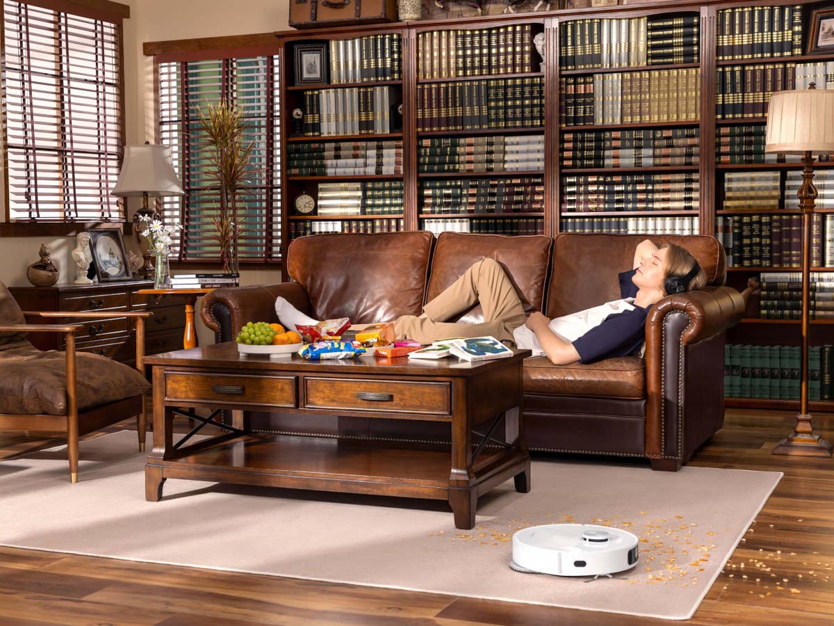 Entspannung mit dem DreameBot L10s Ultra Mann entspannt sich auf der Couch während Roboter staubsaugt
