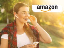 Eine Frau steckt sich einen Kopfhörer ins Ohr und lacht