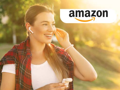 Eine Frau steckt sich einen Kopfhörer ins Ohr und lacht