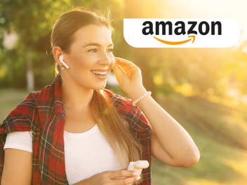 Eine Frau steckt sich einen Kopfhörer ins Ohr und lacht