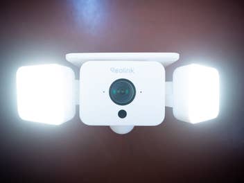 Die Reolink Solar Floodlight Cam an einer roten Wand.