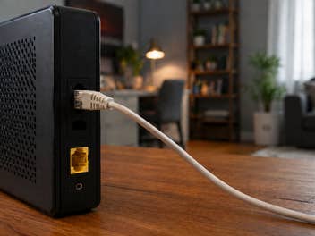 Ein Modem steht auf einem Tisch, im Hintergrund ein Wohnzimmer