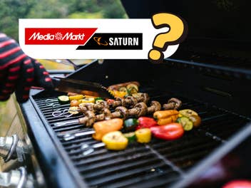 Ein Grill, auf dem Gemüse-Sticks liegen, und eine Hand mit Grillzange, die das Gemüse wendet. Oben links das MedaiMarkt/Saturn-Logo und ein Fragezeichen.