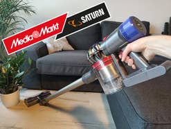 Eine Person hält den Dyson V8 in der Hand und saugt damit einen Wohnbereich.