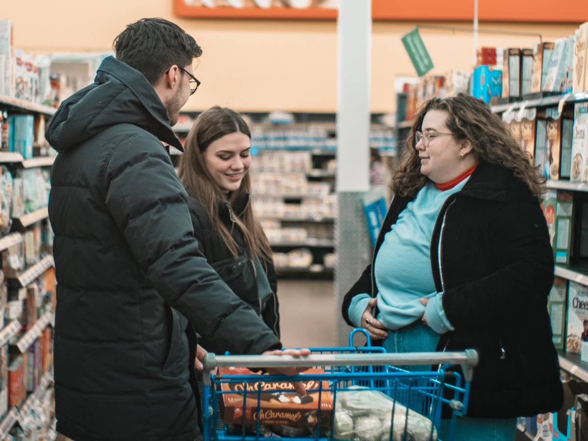 Drei Menschen stehen in einem Supermarkt.