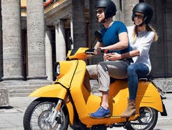 Ein Mann und eine Frau sitzen auf einem Roller und fahren durch die Stadt