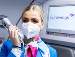 Flugbegleiterin von Eurowings macht eine Durchsage in der Kabine eines Flugzeugs.