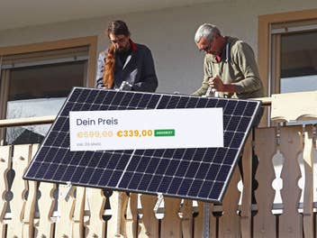 Zwei Personen bringen ein Balkonkraftwerk an. Darauf abgebildet ein aktuelles Angebot für 339 Euro