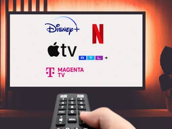 Fernbedienung auf einen TV gerichtet, auf dem die Logos von verschiedenen Streamingdiensten wie Netflix und Disney+ zu sehen sind