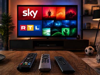 Blick in ein Wohnzimmer, auf dem TV-Gerät unter anderem Logos von Sky und RTL, auf einem Tisch drei Fernbedienungen