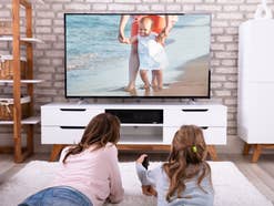 Eine Frau und ihre Tochter liegen vor einem Fernseher im Wohnzimmer
