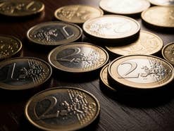 Euro-Geldmünzen liegen im Sonnenlicht auf einem Tisch.