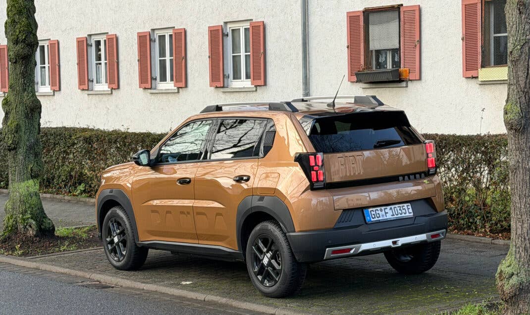 Fiat Grnade Panda Elektro steht in einer Parklücke zwischen Bäumen.