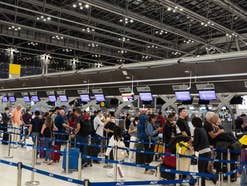 Menschen stehen vor dem Check-in Schalter einer Airline am Flughafen