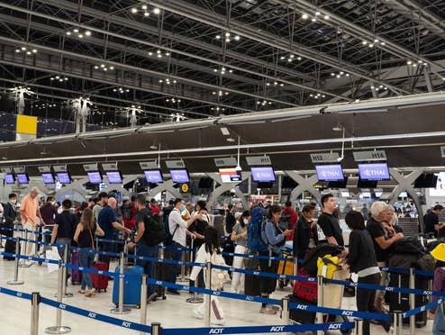 Menschen stehen vor dem Check-in Schalter einer Airline am Flughafen