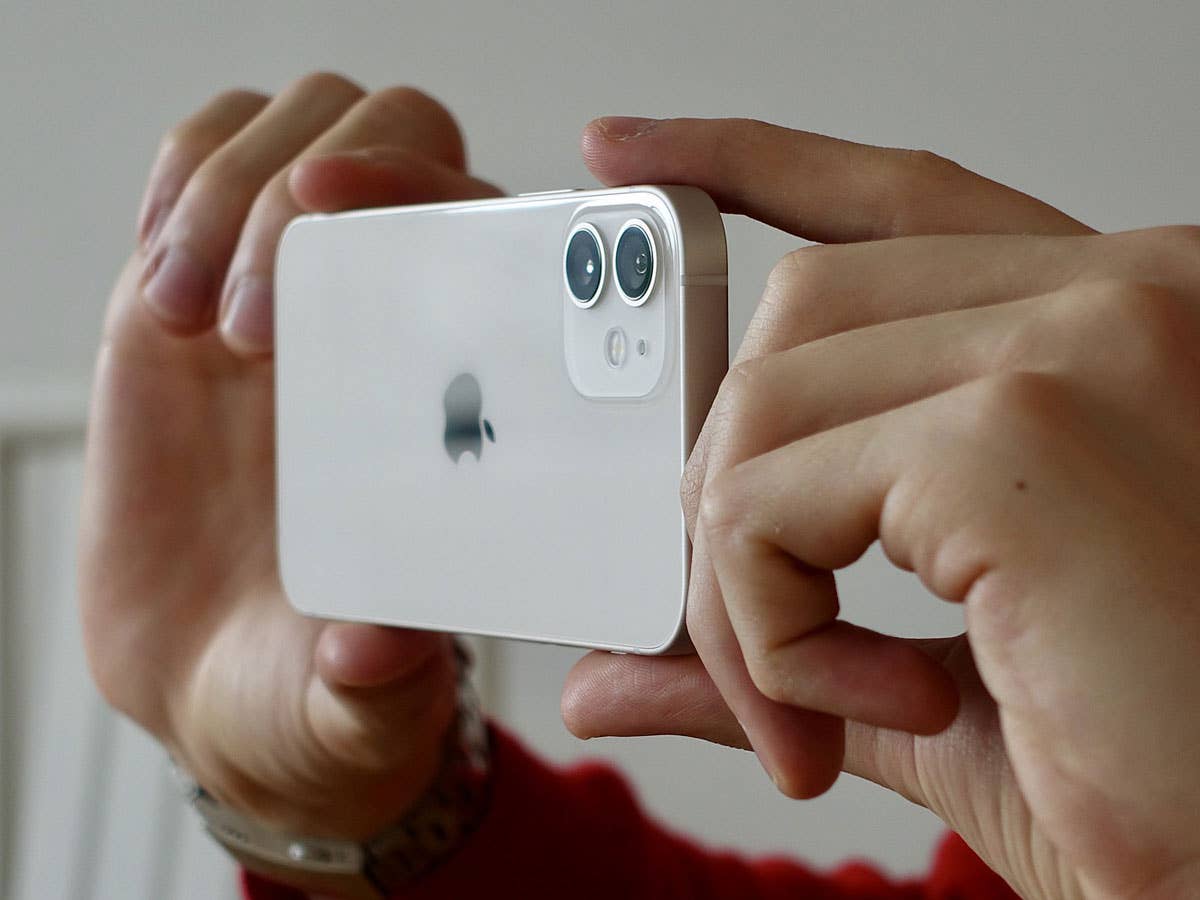 Jemand fotografiert mit einem iPhone 12 in beiden Händen