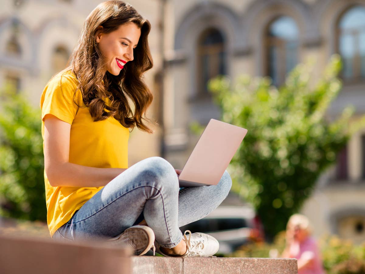 Frau arbeitet draußen mit einem Laptop