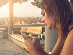 Eine Frau schaut im Urlaub auf ihr Handy