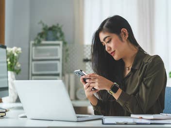 Frau im Homeoffice mit Smartphone und Laptop