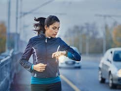 Eine Frau schaut beim Joggen auf ihre Smartwatch