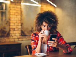 Frau trinkt Kaffee und schaut auf ihr Smartphone