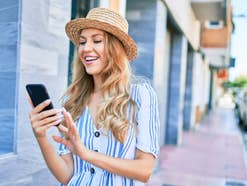 Frau läuft durch die Innenstadt und schaut auf ihr Smartphone