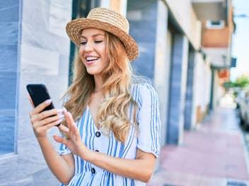 Frau läuft durch die Innenstadt und schaut auf ihr Smartphone