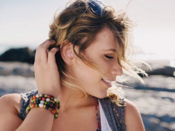 Eine Frau trägt JBL In-Ear-Kopfhörer am Strand