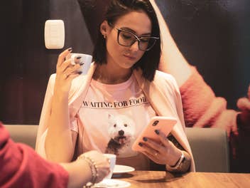 Eine Frau sitzt im caé und blickt auf ihr iPhone