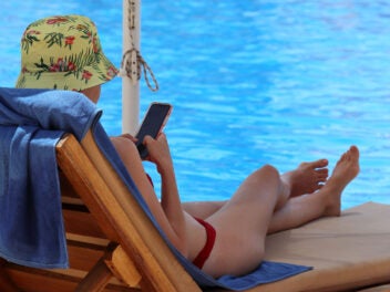 Frau mit Smartphone am Pool