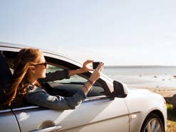 Frau fotografiert mit dem Smartphone aus dem Auto