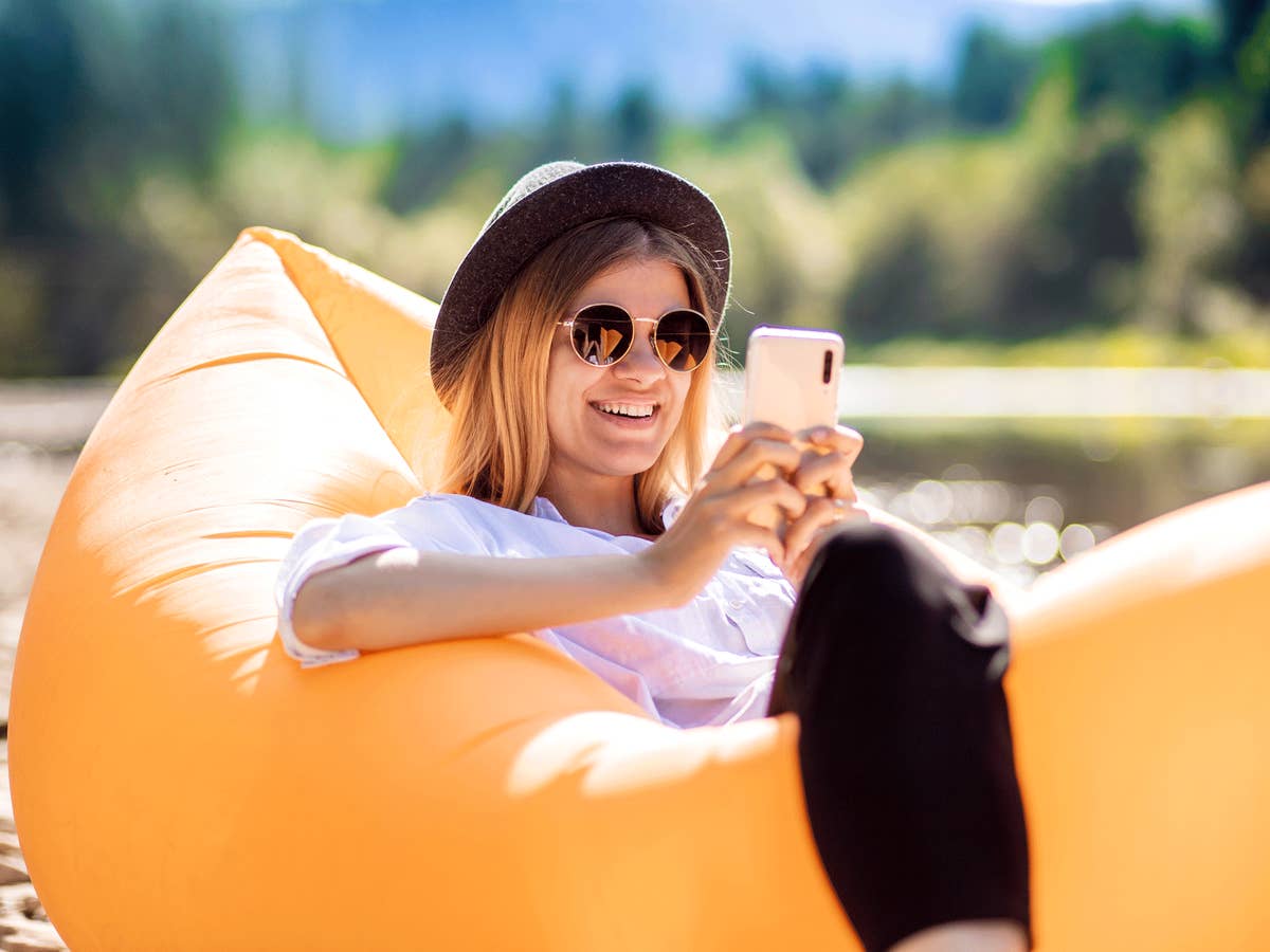 Eine Frau mit Sonnenbrille und Smartphone in einem Gummiboot