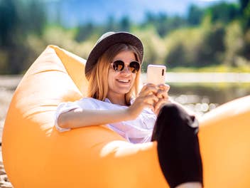 Eine Frau mit Sonnenbrille und Smartphone in einem Gummiboot
