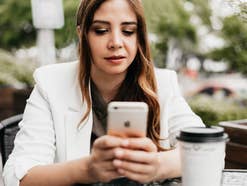 Eine Frau sitzt mit einem Smartphone in einem Kaffee