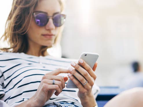 Frau mit Sonnenbrille schaut auf ihr Smartphone