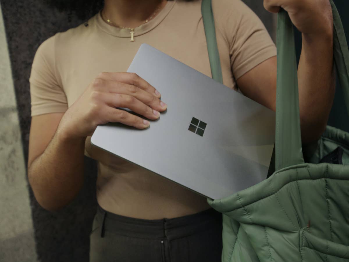 Eine Frau hat ein Windows-Tablet in der Hand und steckt es in ihre Tasche.