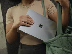 Eine Frau hat ein Windows-Tablet in der Hand und steckt es in ihre Tasche.