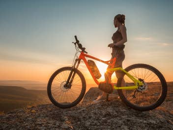 Frau neben einem E-Mountainbike in den Bergen.