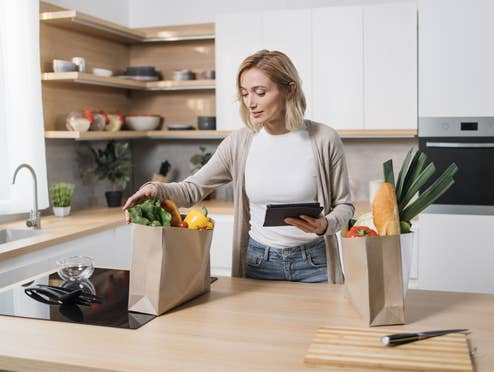Frau packt Einkäufe mit Lebensmitteln in der Küche aus