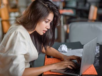 Frau schaut gestresst auf einen Laptop