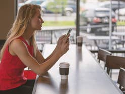 Eine Frau sitzt mit einem Smartphone in einem Café am Tisch