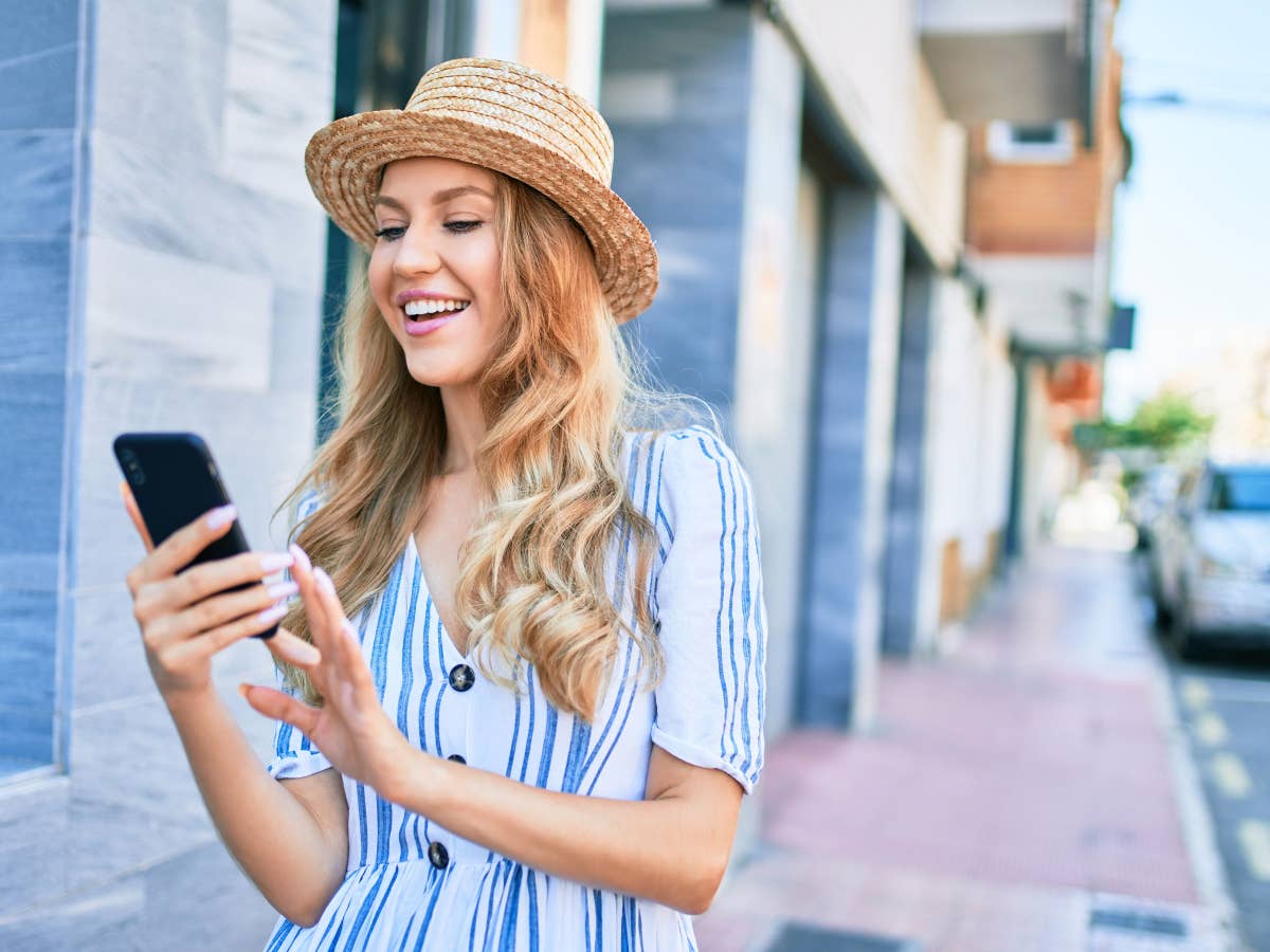 Eine Frau lächelt und blickt auf ihr Smartphone