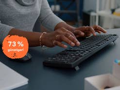 Eine Frau schreibt auf einer schwarzen Tastatur auf ihrem Schreibtisch