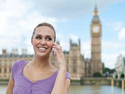 Eine Frau steht in London vor dem Tower of London und telefoniert mit dem Handy