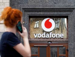 Eine Frau telefoniert mit dem Handy, Vodafone-Logo im Hintergrund