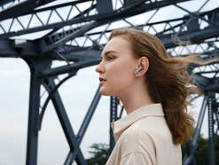 Frau mi Huawei Freebuds Kopfhörern Eine Frau trägt Huawei Freebuds Kopfhörer unterwegs