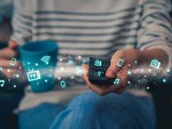 Eine Frau hält eine TV-Fernbedienung in der Hand, Streaming-Symbole sind zu sehen