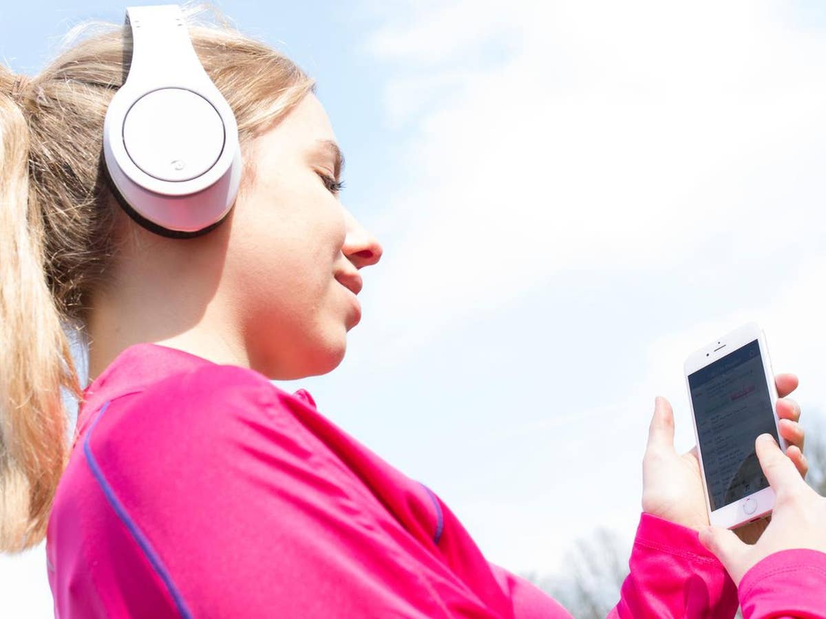 Eine Frau hört Radio mit Smartphone und Kopfhörer